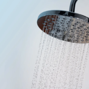 Chuveiro moderno com água fluindo em gotas claras contra fundo azul e branco