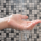 Imagem de uma mão sob água corrente, representando o uso de aquecedor de água para aquecer o banho ou torneira.