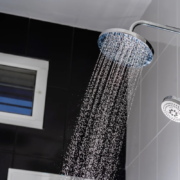 Chuveiro moderno com água corrente em banheiro com azulejos pretos e brancos