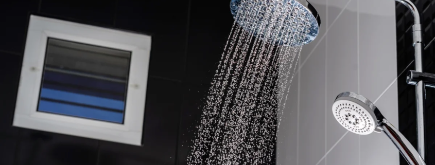 Chuveiro moderno com água corrente em banheiro com azulejos pretos e brancos