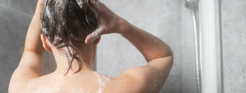 Pessoa lavando o cabelo com shampoo no chuveiro com espuma