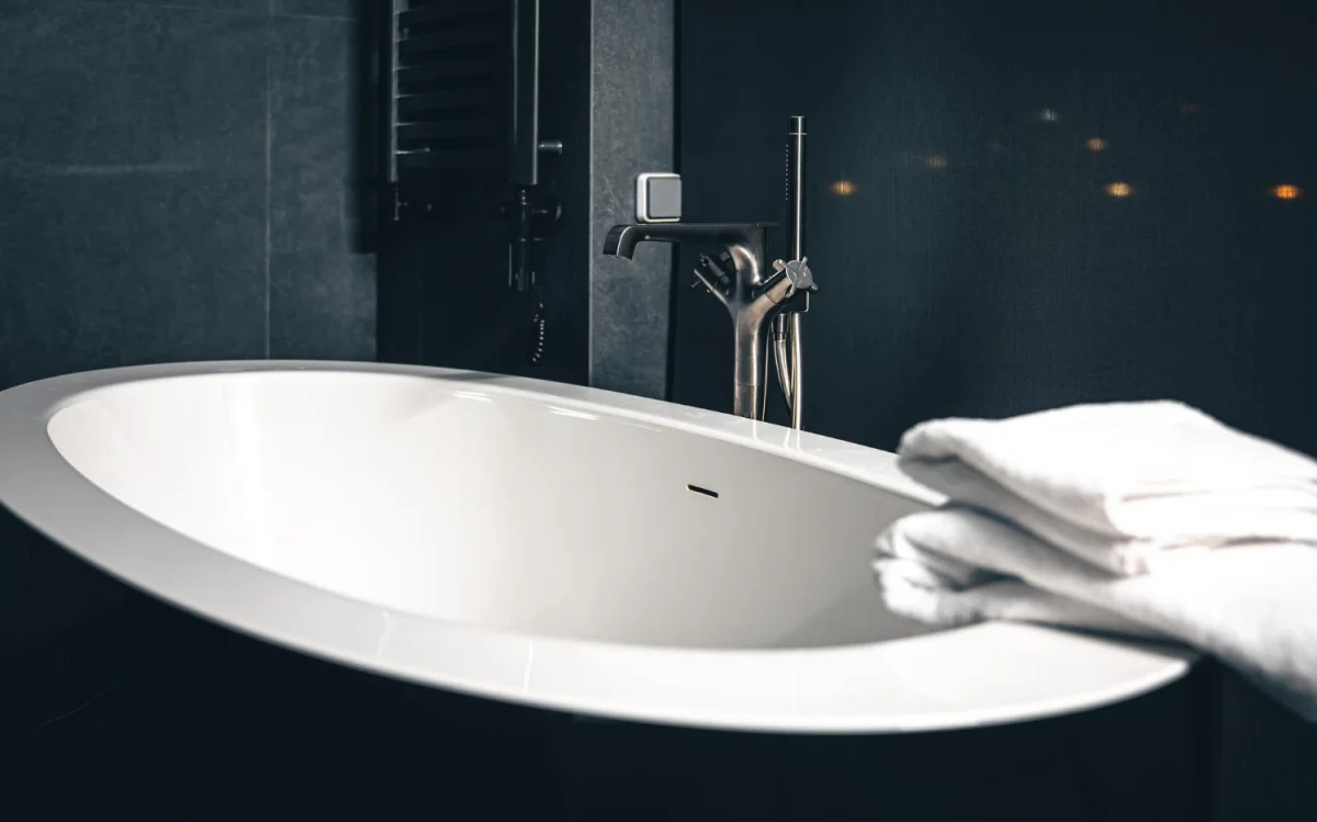 Banheira branca moderna com torneira preta e toalhas brancas